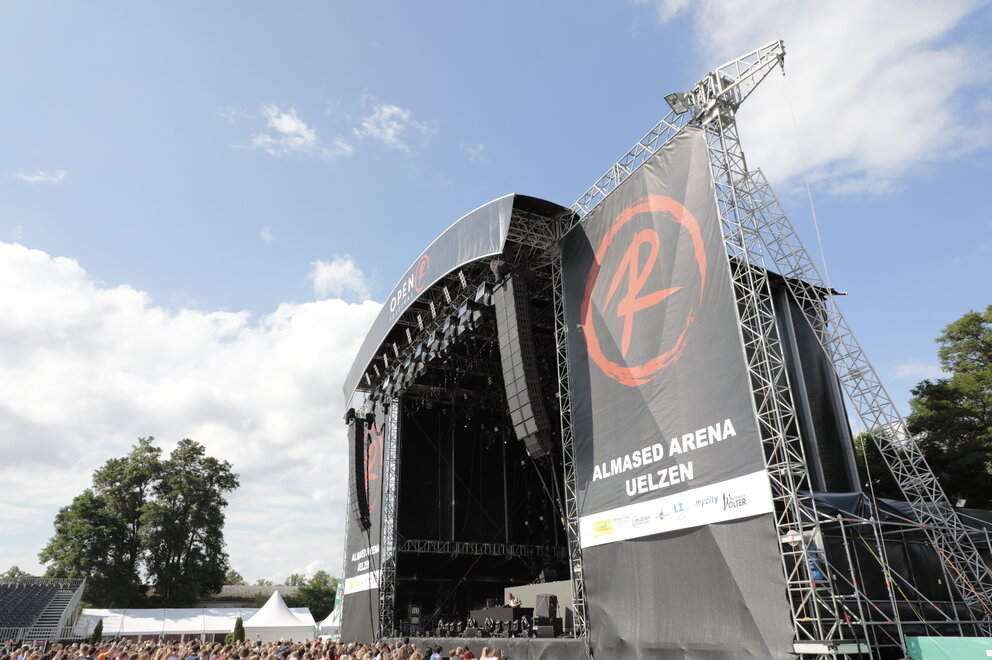 Nahaufnahme von linker Reihe in der Menge vor einer großen Bühne mit Aufschrift "Almased Arena Uelzen"