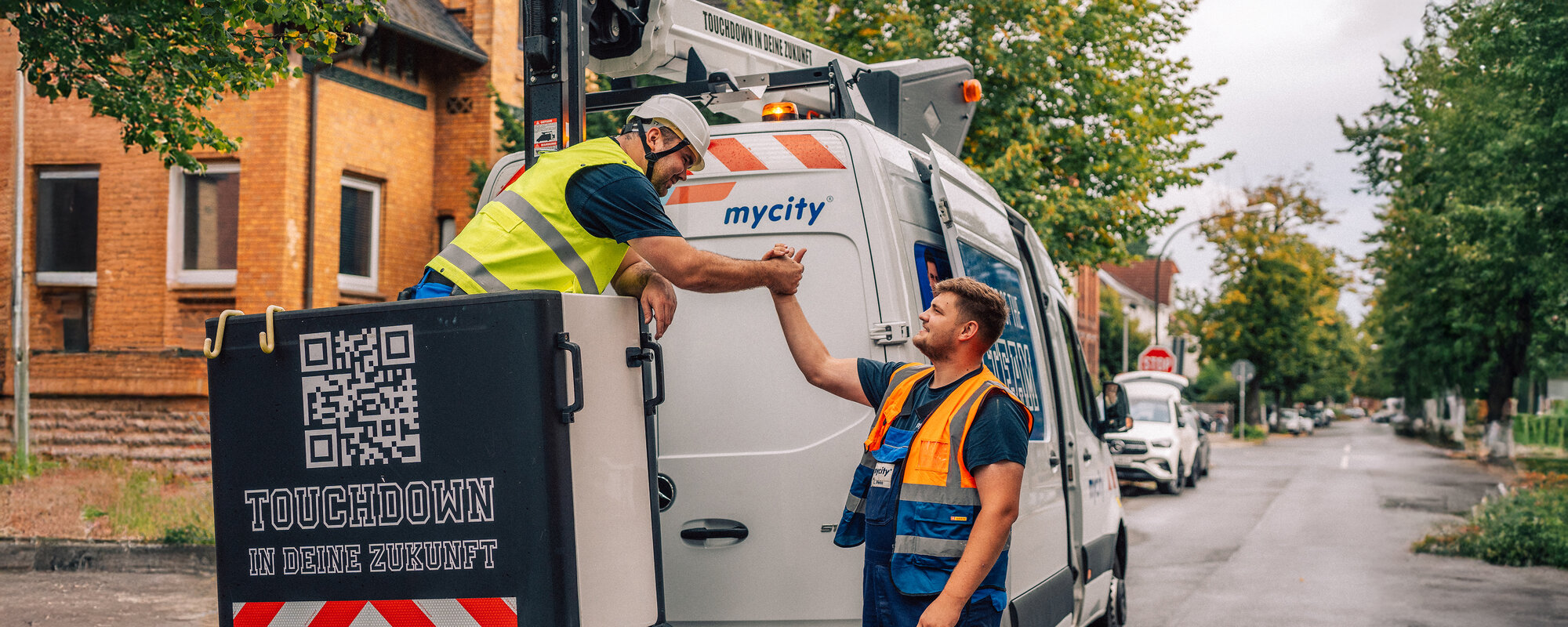 Zwei mycity Techniker geben sich einen Handschlag vor einem mycity Baustellenfahrzeug