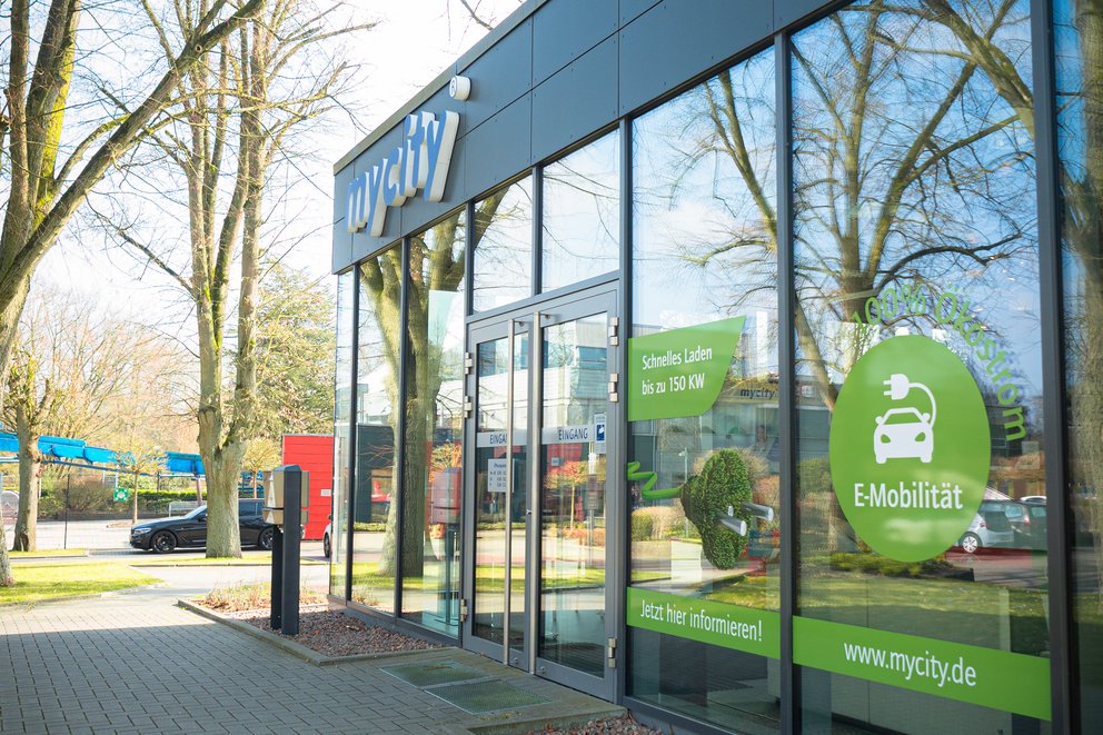 Ein komplett verglastes Gebäude, das mycity Service Center mit einer Steinfläche daneben.