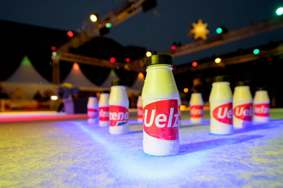 Auf einer Eisbahn stehen Flaschen mit der Aufschrift "Uelzen"