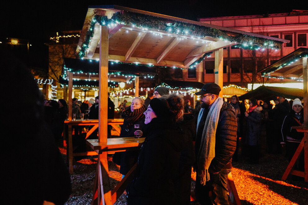 Ein Weihnachtsmarkt Stand an dem eine Frau steht und lächelt.