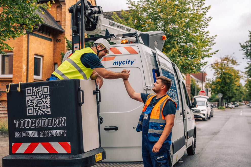 Zwei mycity Techniker geben sich einen Handschlag vor einem mycity Baustellenfahrzeug