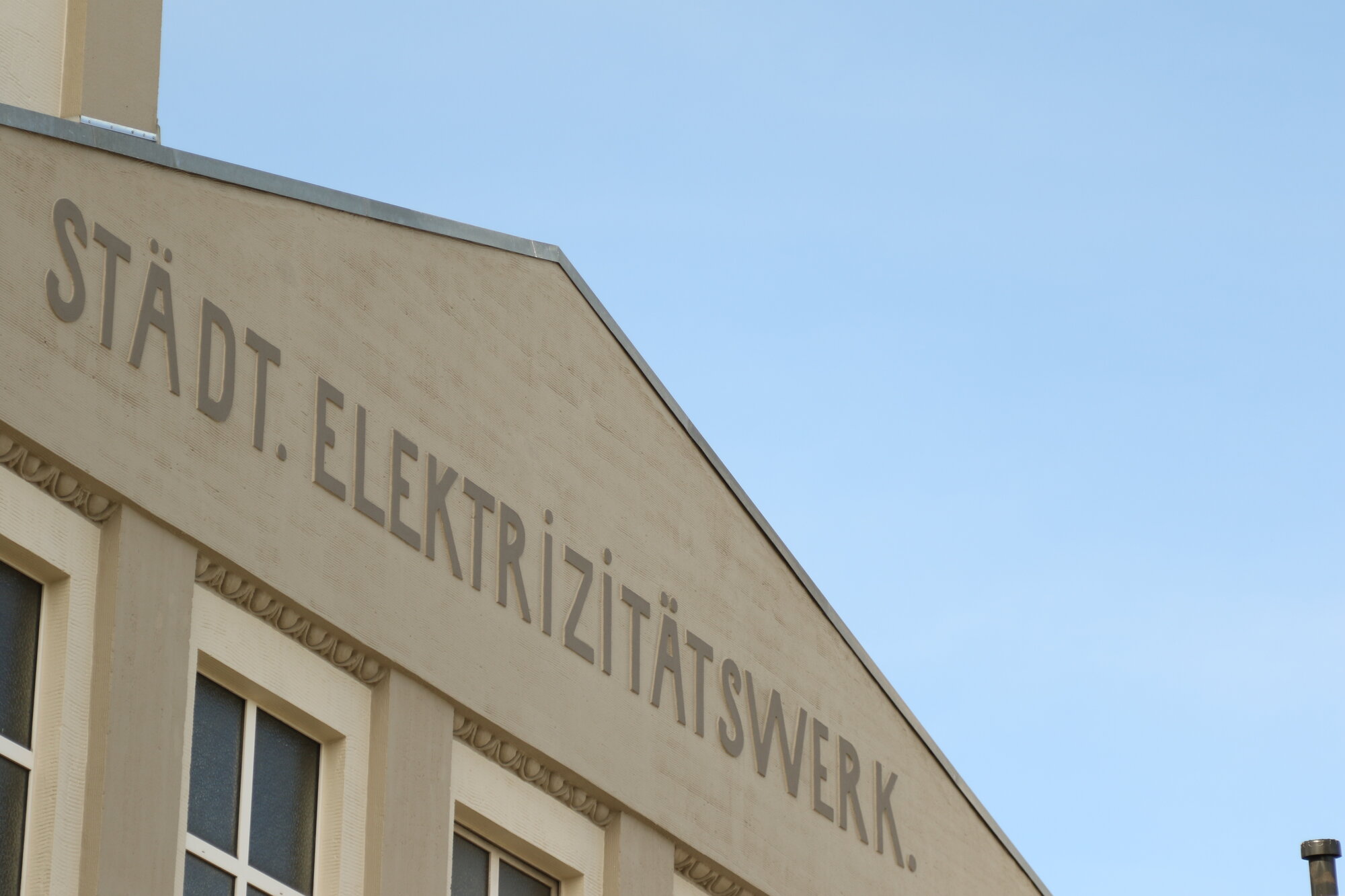 Außenaufnahme des Städtischen Elektrizitätswerks in Uelzen, ein beiges Gebäude mit Zoom auf die Aufschrift.