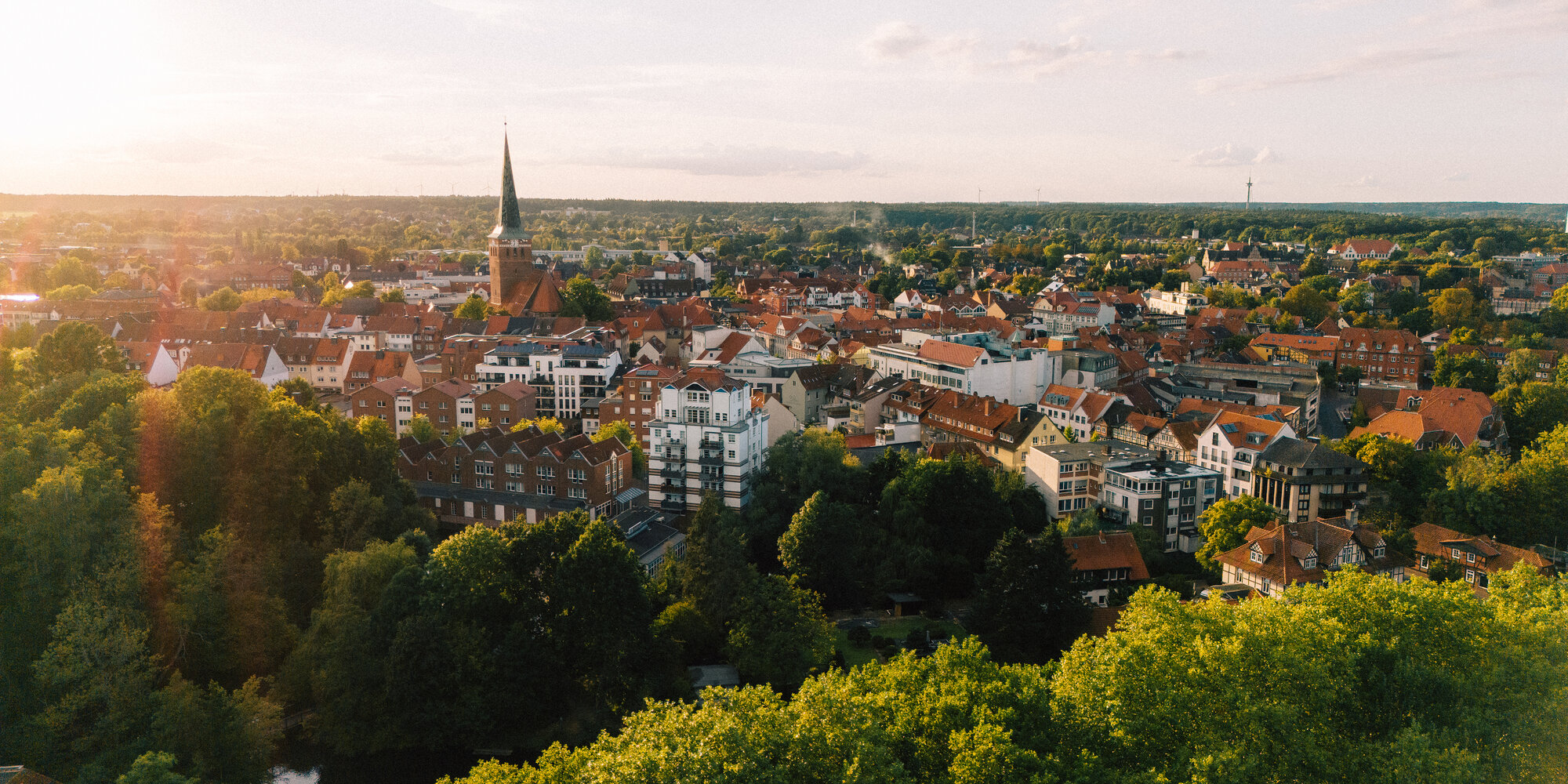 Luftaufnahme der Uelzener Skyline mit Häusern & Kirche zwischen vielen Bäumen.