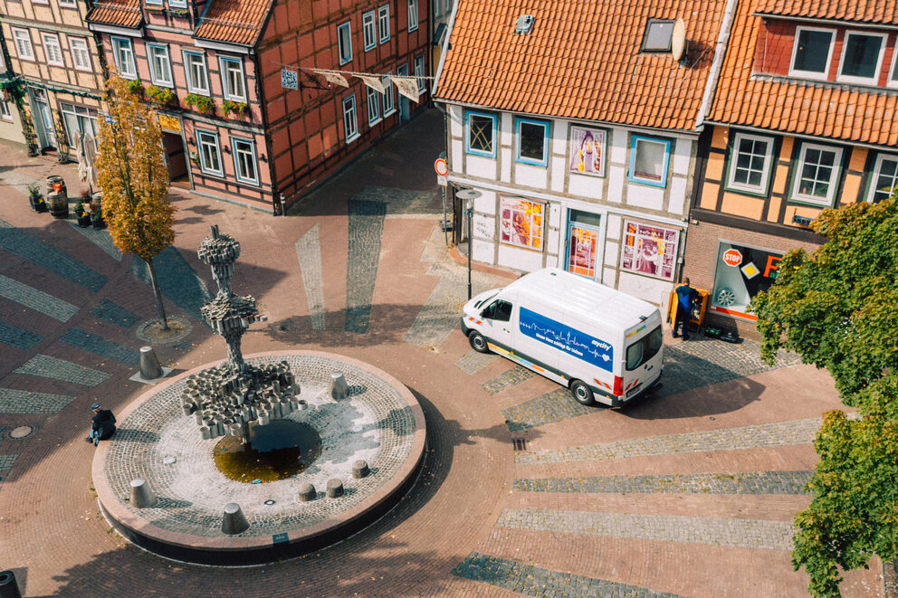 Mycity_Uelzen.jpg Luftaufnahme vom Brunnen am Schnellenmarkt in Uelzen mit mycity Techniker*innen im Einsatz am Stromkasten