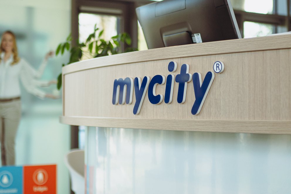 Ein Service Center Desk mit dunkelblauem Schriftzug mycity darauf und einigen Motiven darunter.