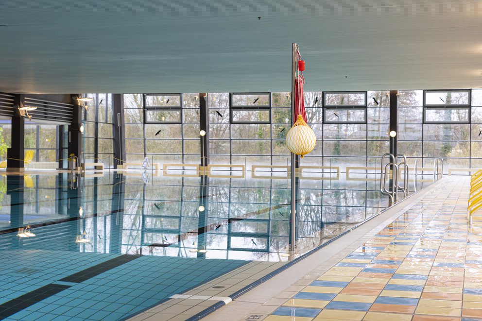 Ein Schwimmbecken im Innenbereich mit Volleyball Leine und Volleyball Netz darin.